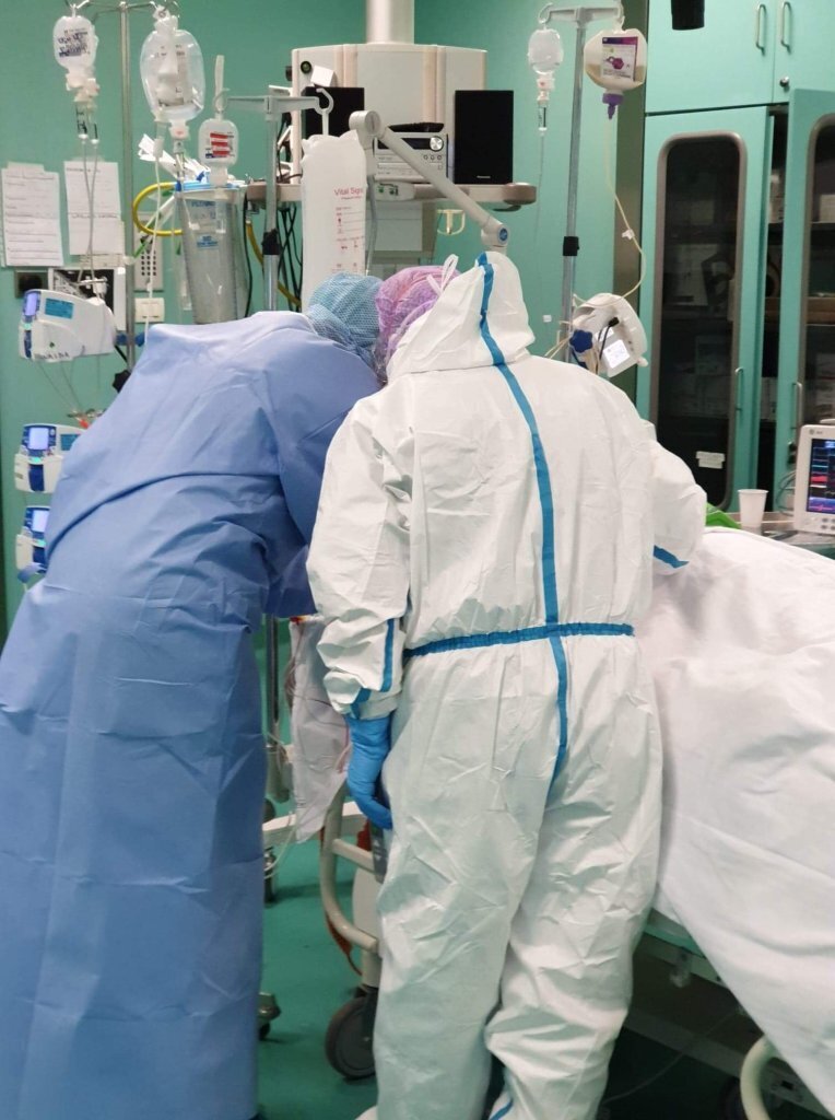 Bildet viser to sykepleiere i smitteverntutstyr på en sykehusstue.