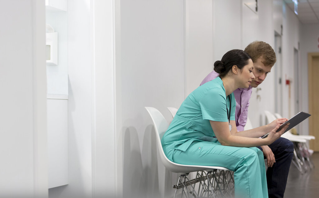Sykepleier og pasient i sykehuskorridor
