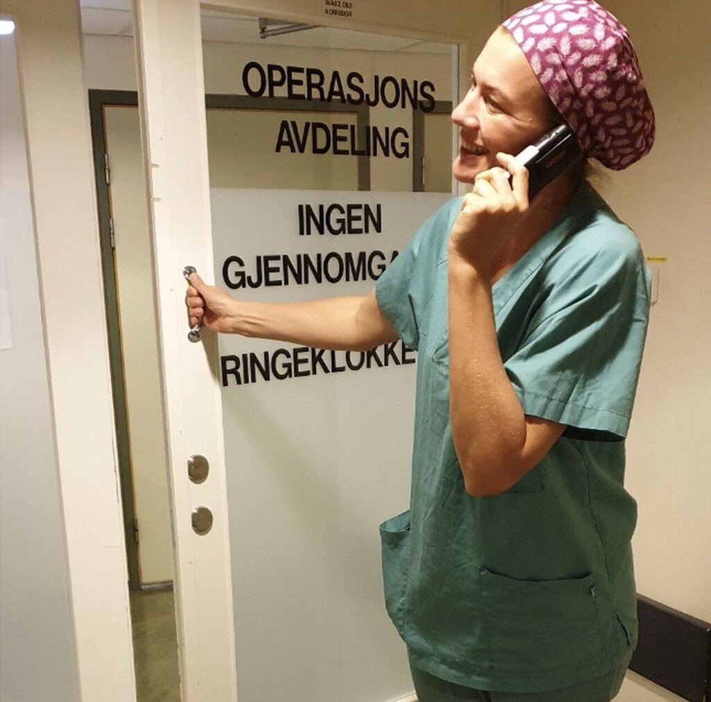 Bildet viser en operasjonssykepleier som åpner døren inn til operasjonsavdelingen.