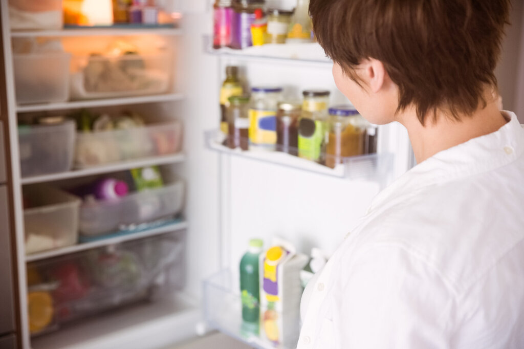 Kvinne kikker inn i fullt kjøleskap.