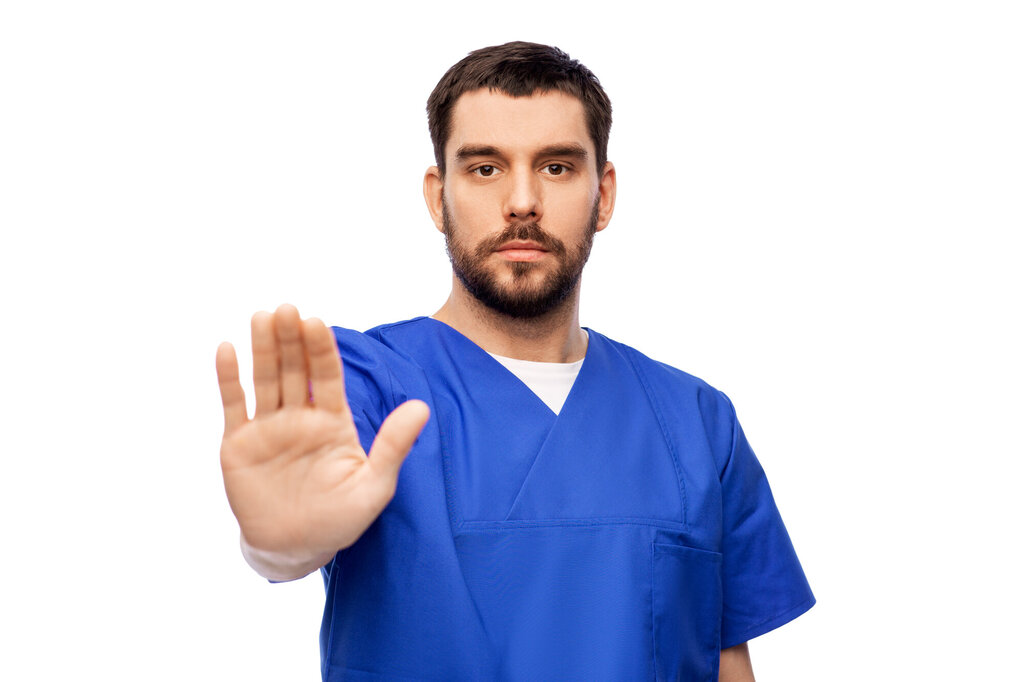 Bildet viser en mannlig sykepleier som viser håndflaten som et tegn på at nok er nok