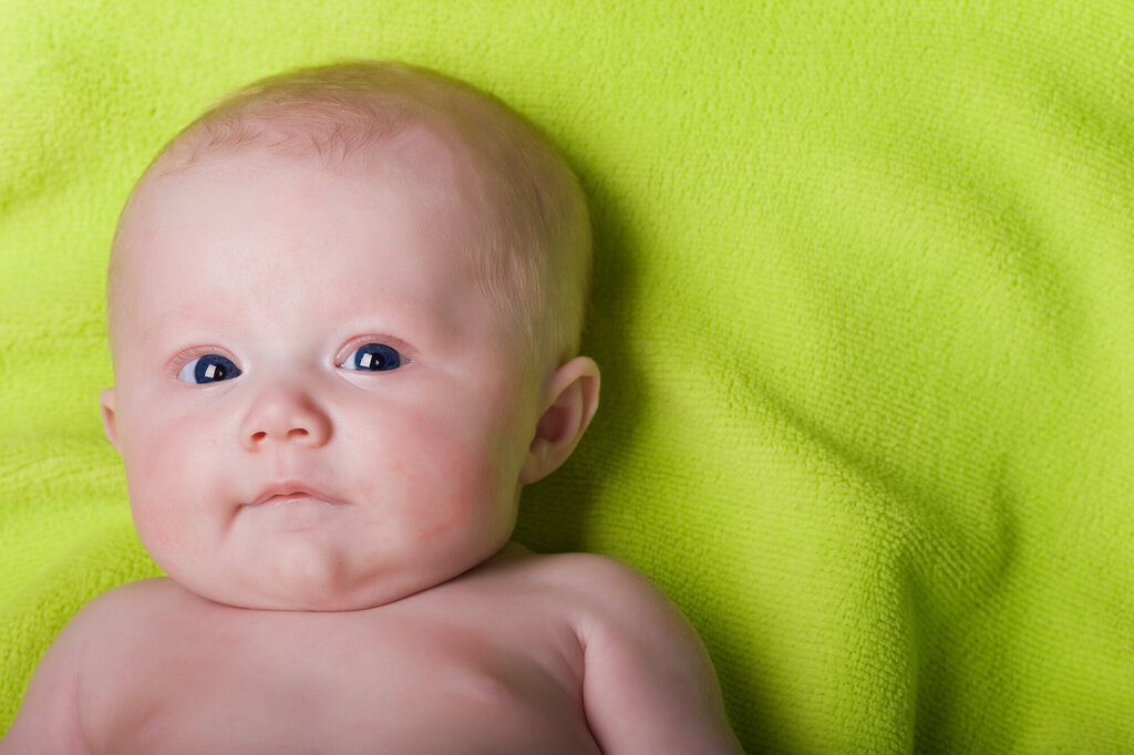 Bildet viser et nyfødt barn som ligger på et grønt teppe
