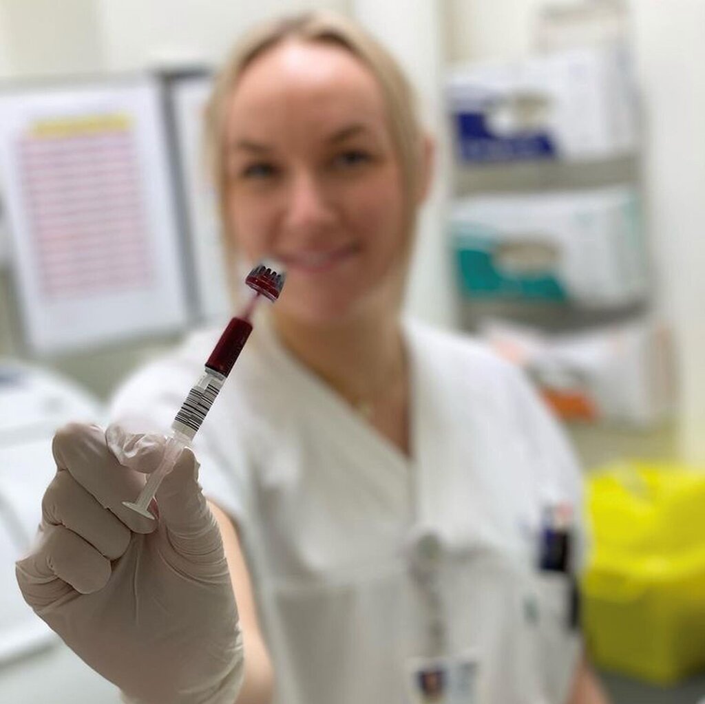 Bildet viser en sykepleier som holder frem en sprøyte med blod til blodgassanalyse.