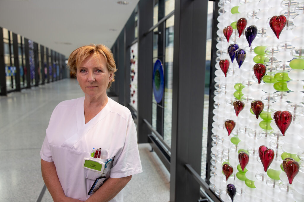 Bildet viser Turid Sparby i glassgangen på Ringerike sykehus, ved siden av hjertene som symboliserer ungdommene som kom til Ringerike sykehus 22. juli 2011.