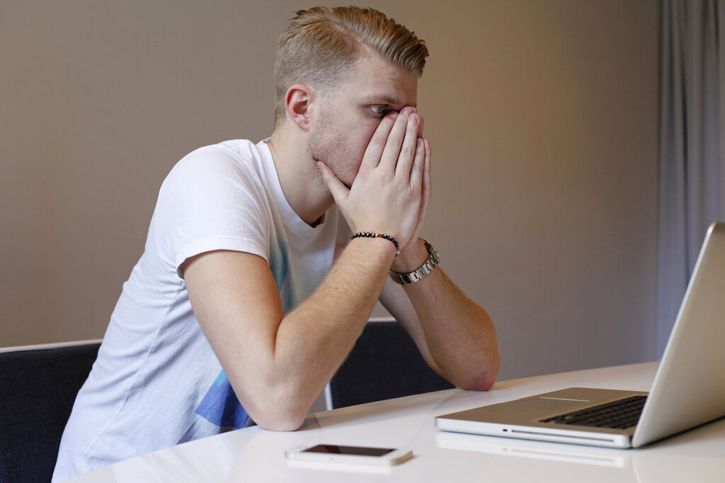 En sliten, ung mann ser på en dataskjerm