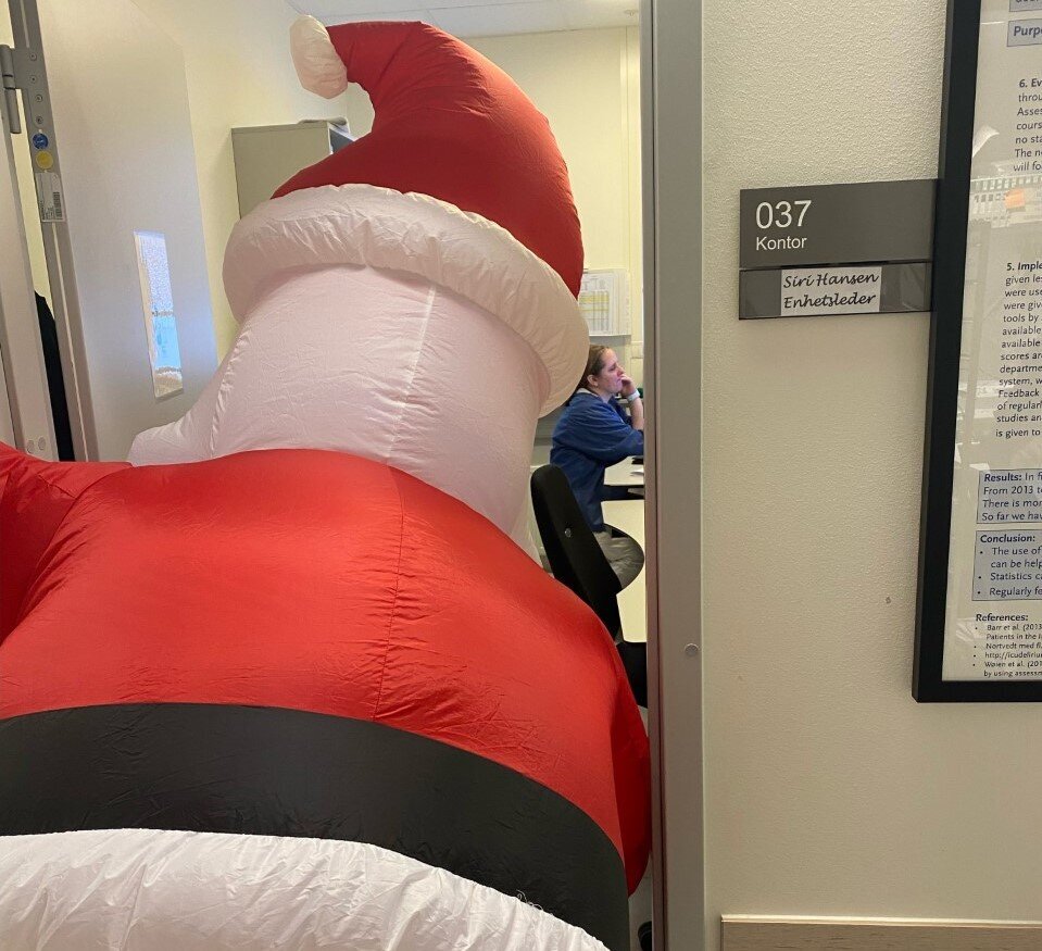 Bildet viser julenissen som titter inn på et kontor på Ahus.