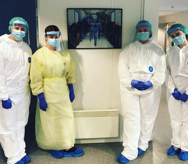 Bildet viser fire ansatte på teststasjonen foran et perlet bilde av sykepleiere.