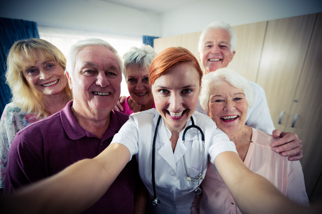 Bildet viser en sykepleier som tar en selfie sammen med flere mennesker