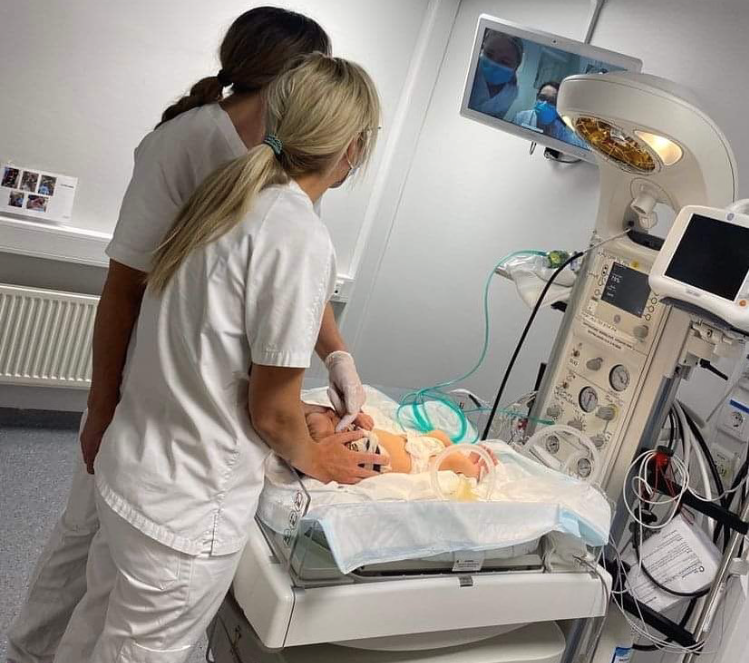Bildet viser helsepersonell som undersøker baby.