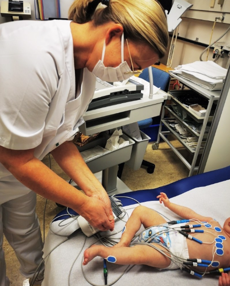 Bildet viser helsepersonell som fester elektroder til kroppen på et barn.