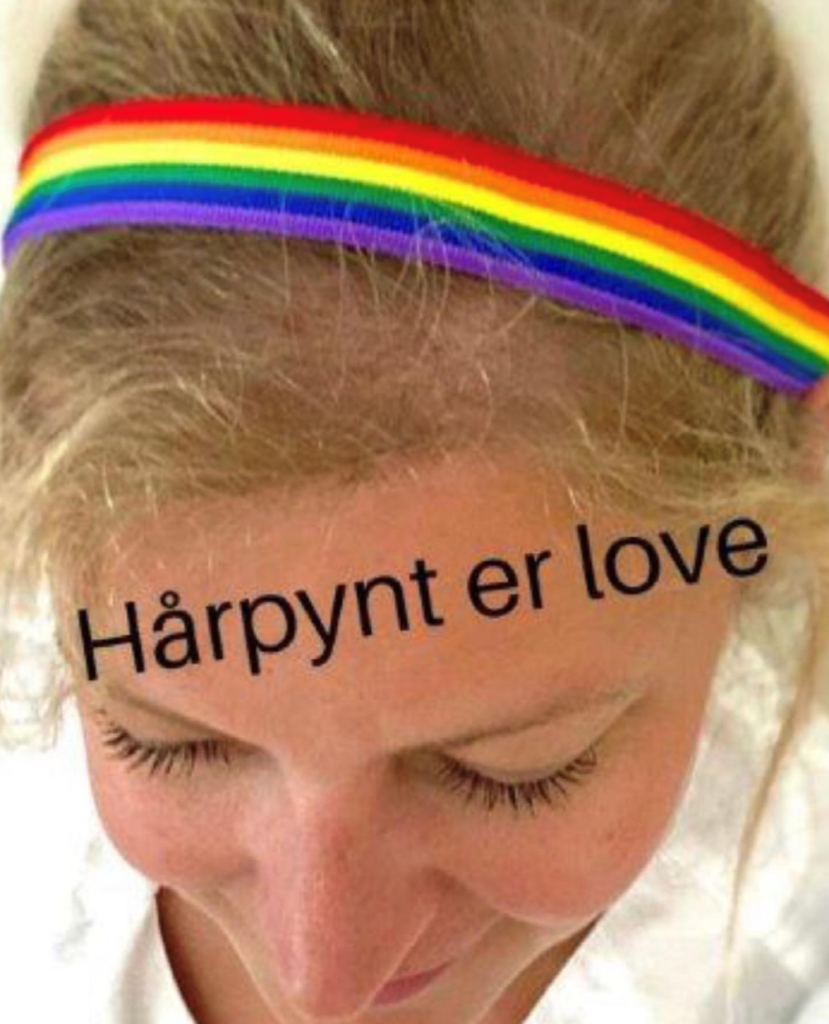 Bildet viser en helsearbeider med hårpynt i regnbuens farger.