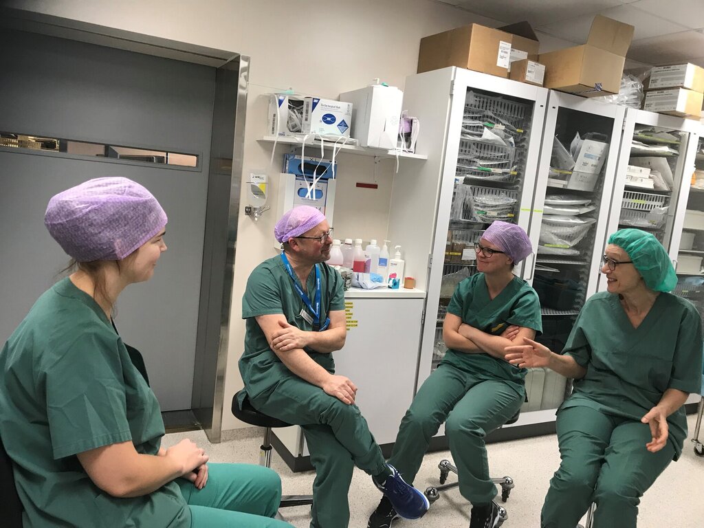 En operasjonssykepleier diskuterer med studenter i et klinisk miljø.