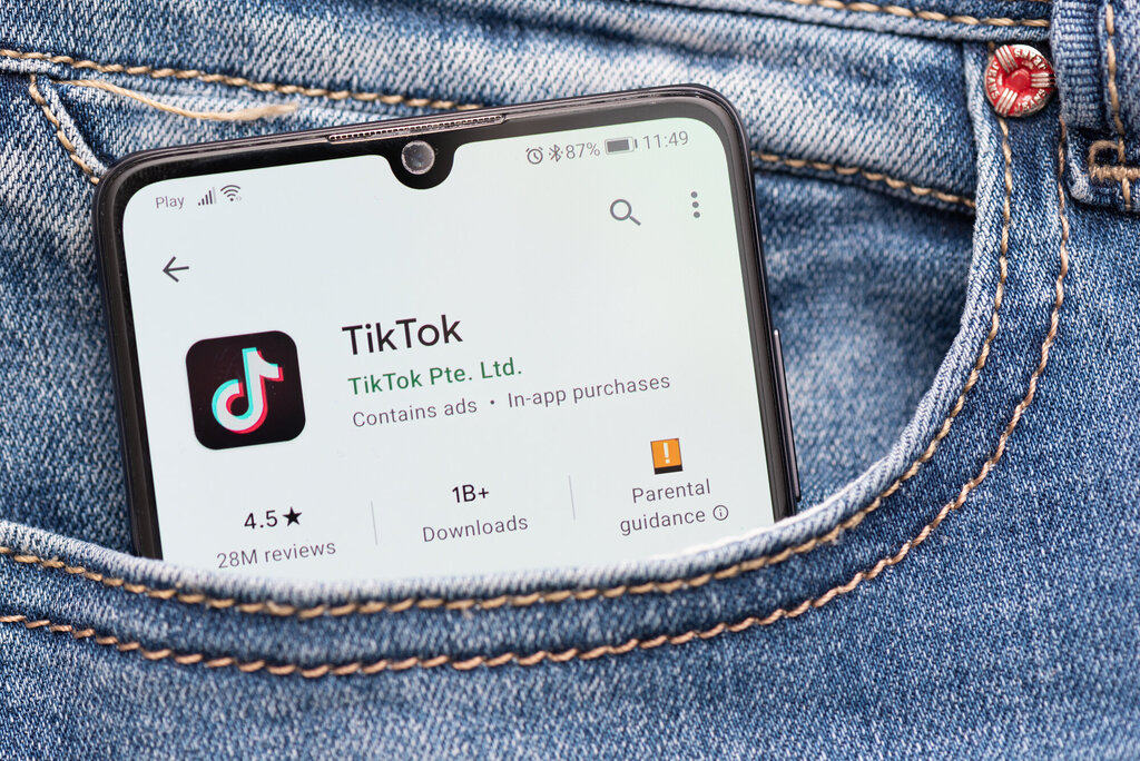 Bildet viser en mobil med TikTok som stikker opp av en bukselomme.