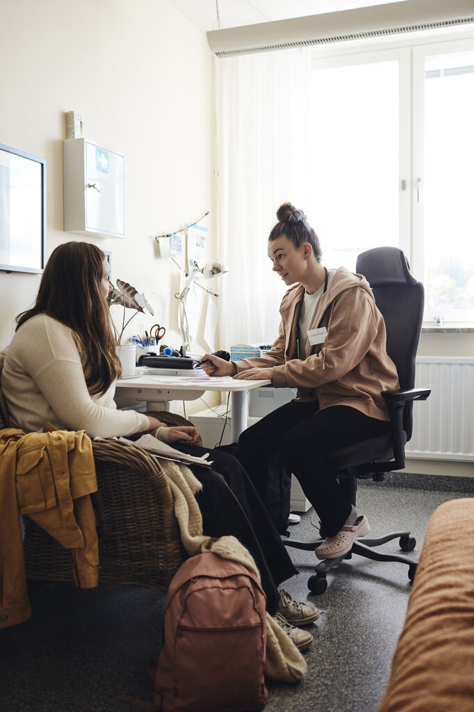 Bildet viser en helsesykepleier som snakker med en elev på et kontor.