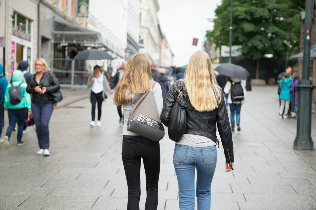 Bildet viser to unge kvinner, fotografert bakfra, som går på gaten