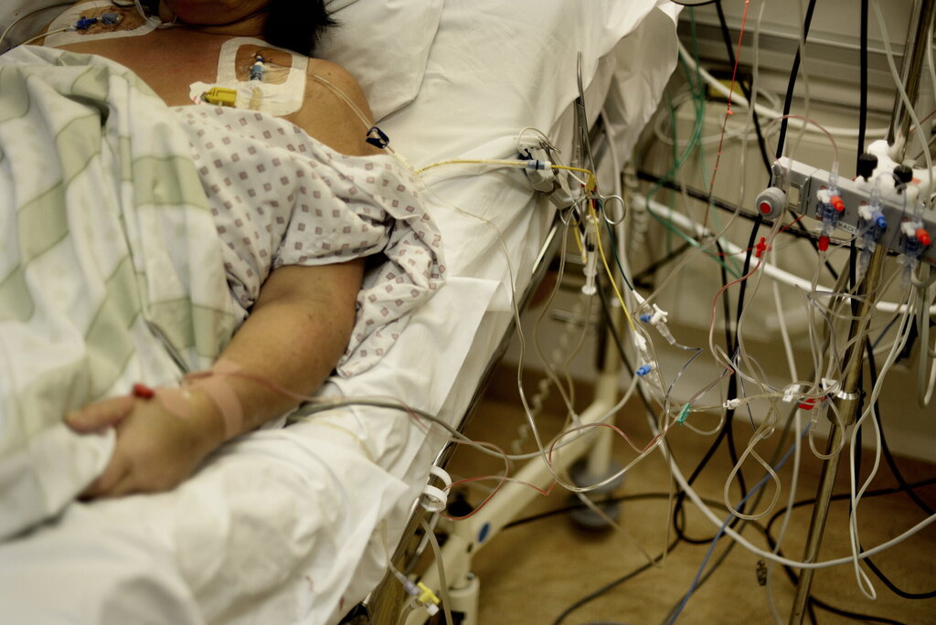 Bildet viser en intensivpasient som ligger i en sykehusseng påkoplet mye medisinsk utstyr