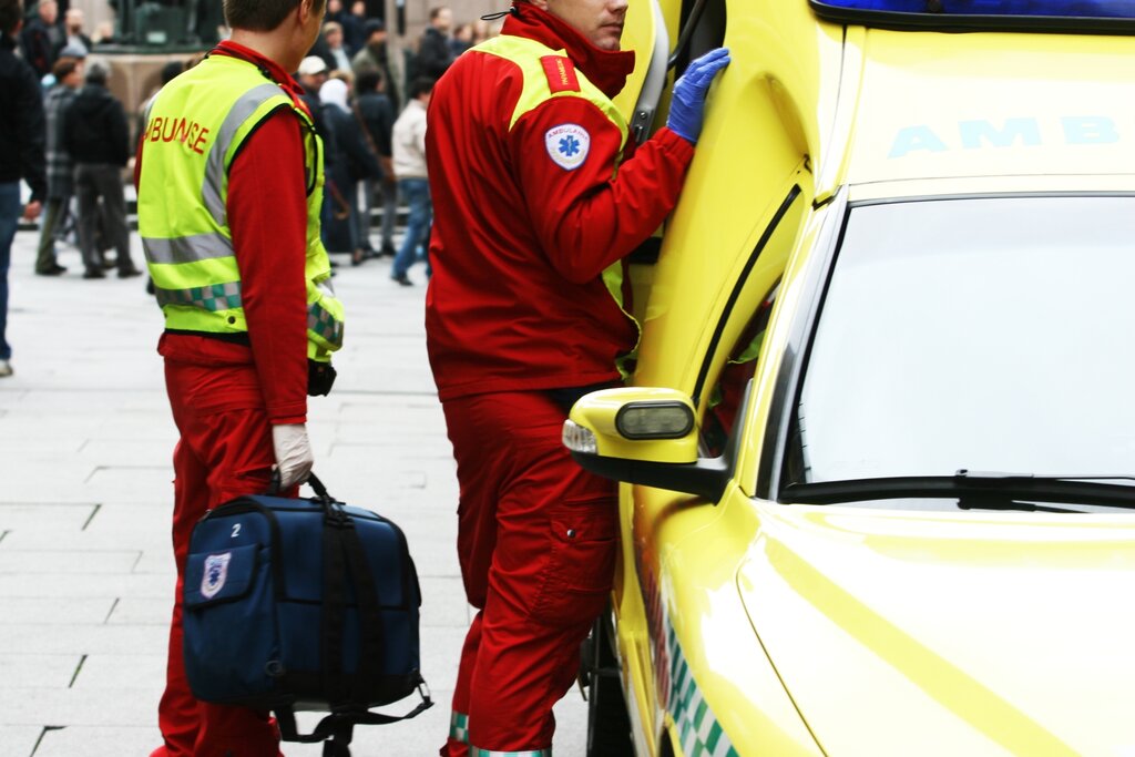 Bilde viser ambulansearbeidere som står utenfor ambulansen i et gatemiljø