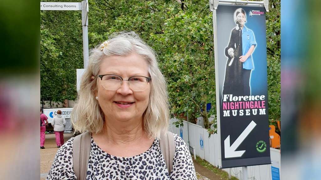 Bildet viser innleggsforfatter Ingeborg Nilsen som står foran en banner med bilde av Florence Nightingale
