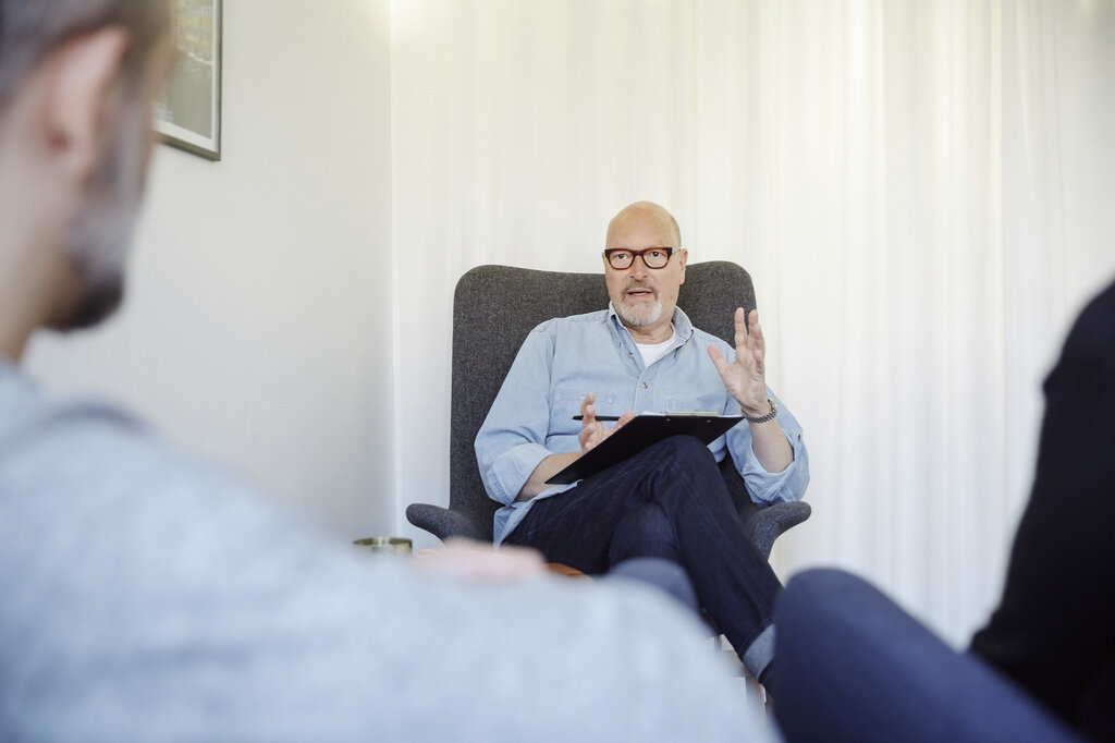 Bildet viser en behandler som snakker med pårørende til en pasient. Pasienten skimtes så vidt i bildet.