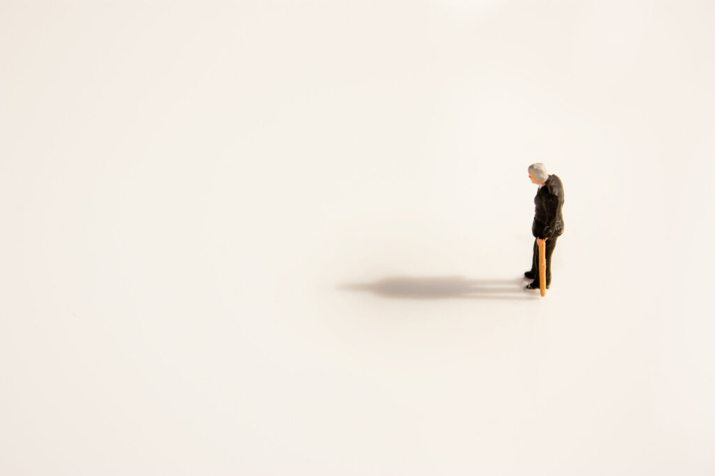 Bildet viser en skulptur av en gammel mann. Han går med stokk og er helt alene.