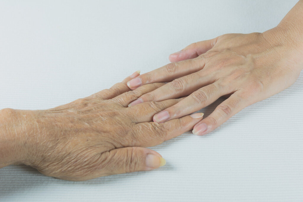 Bilde av en ung hånd som berører en gammel hånd.