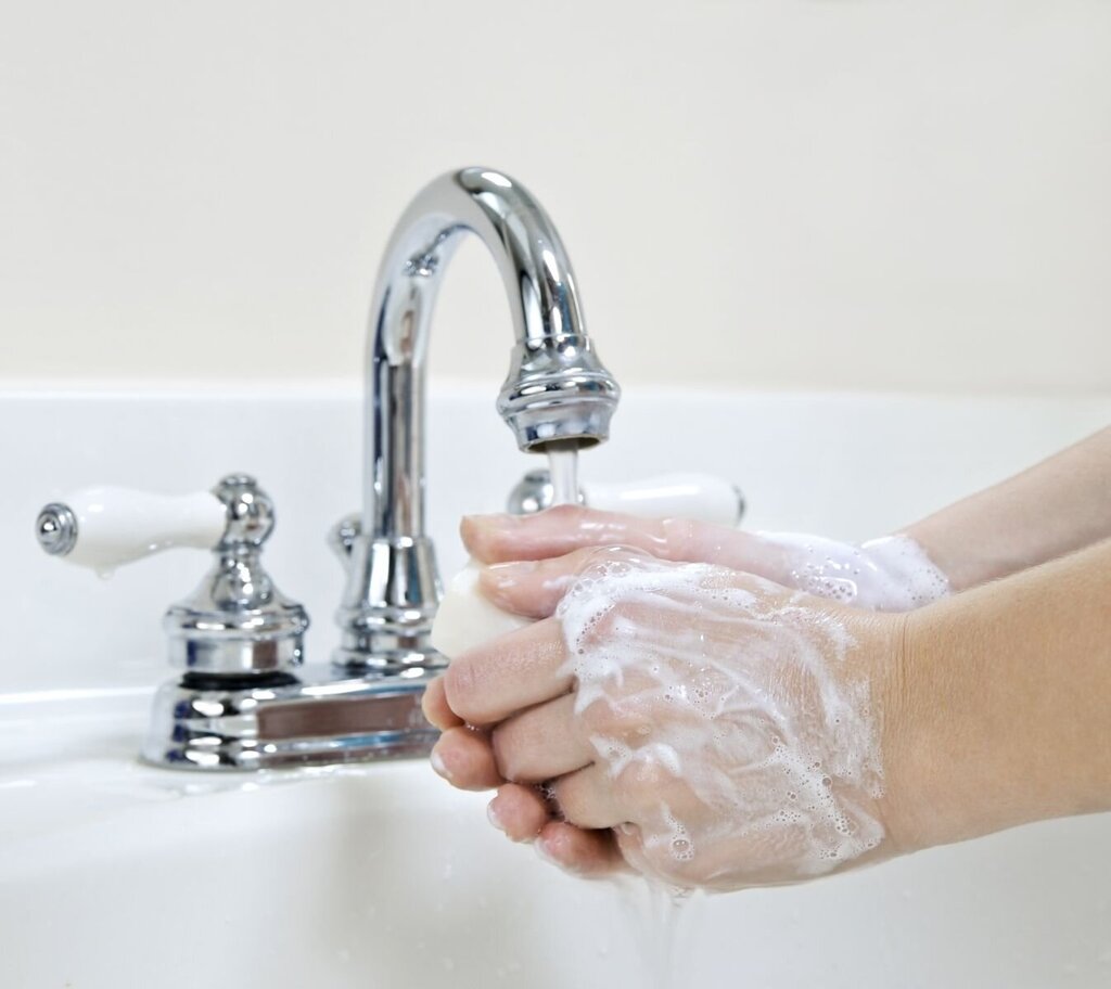 Bildet viser et par hender innsmurt av såpe, som vaskes i springen