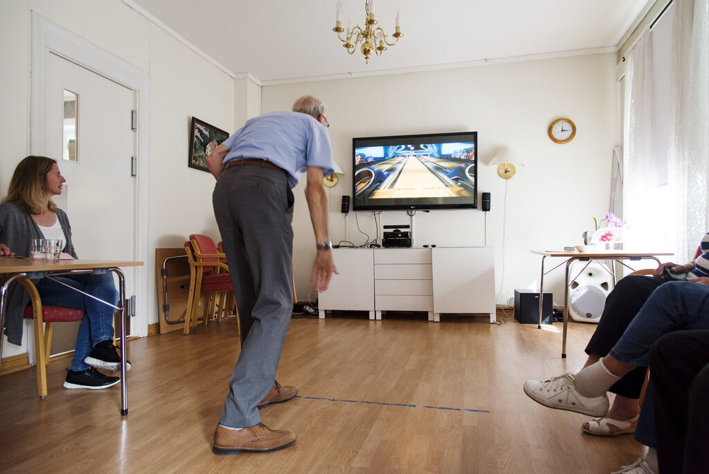 Bildet viser en eldre mann som spiller bowling med Kinect.