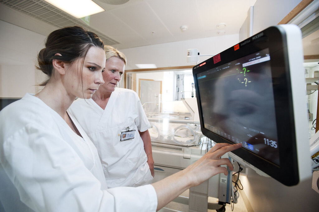 Bildet viser to sykepleiere som ser på monitoren på nyfødtintensiven.