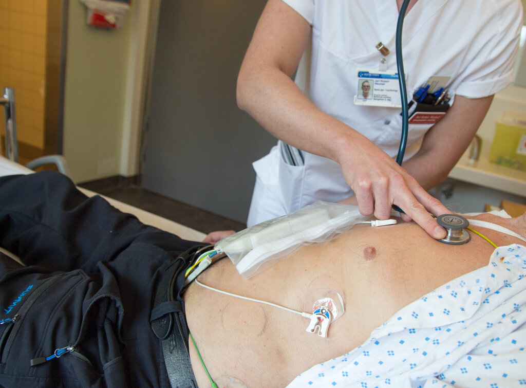 Bildet viser en sykepleier som lytter på brystet til en pasient.