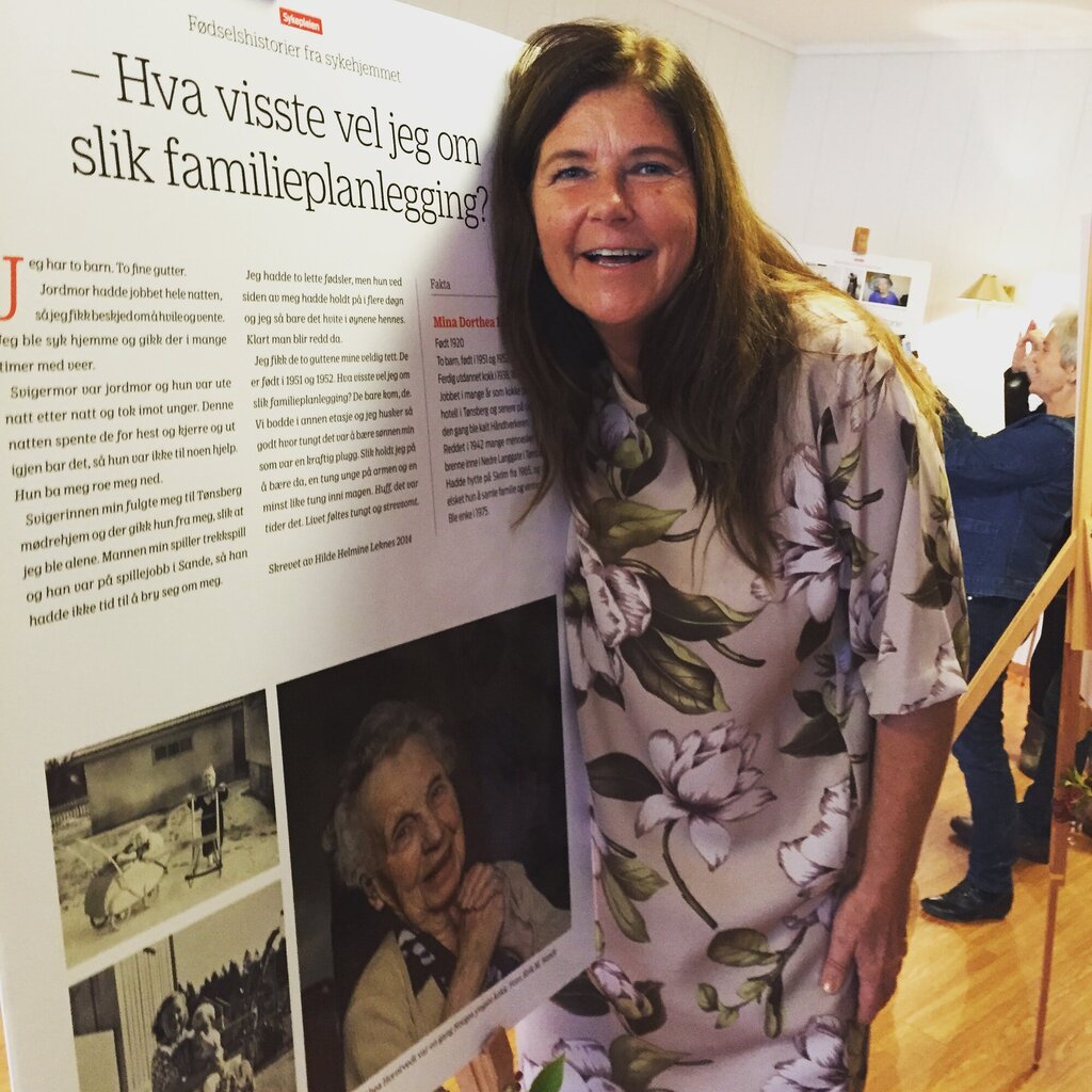 Bildet viser Hilde Helmine Leknes som holder rundt en av historiene som er stilt ut, plakat på staffeli.