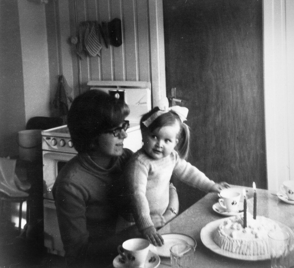 Bildet viser Karin Jonli som sitter på fanget til mamma med kake på bordet.