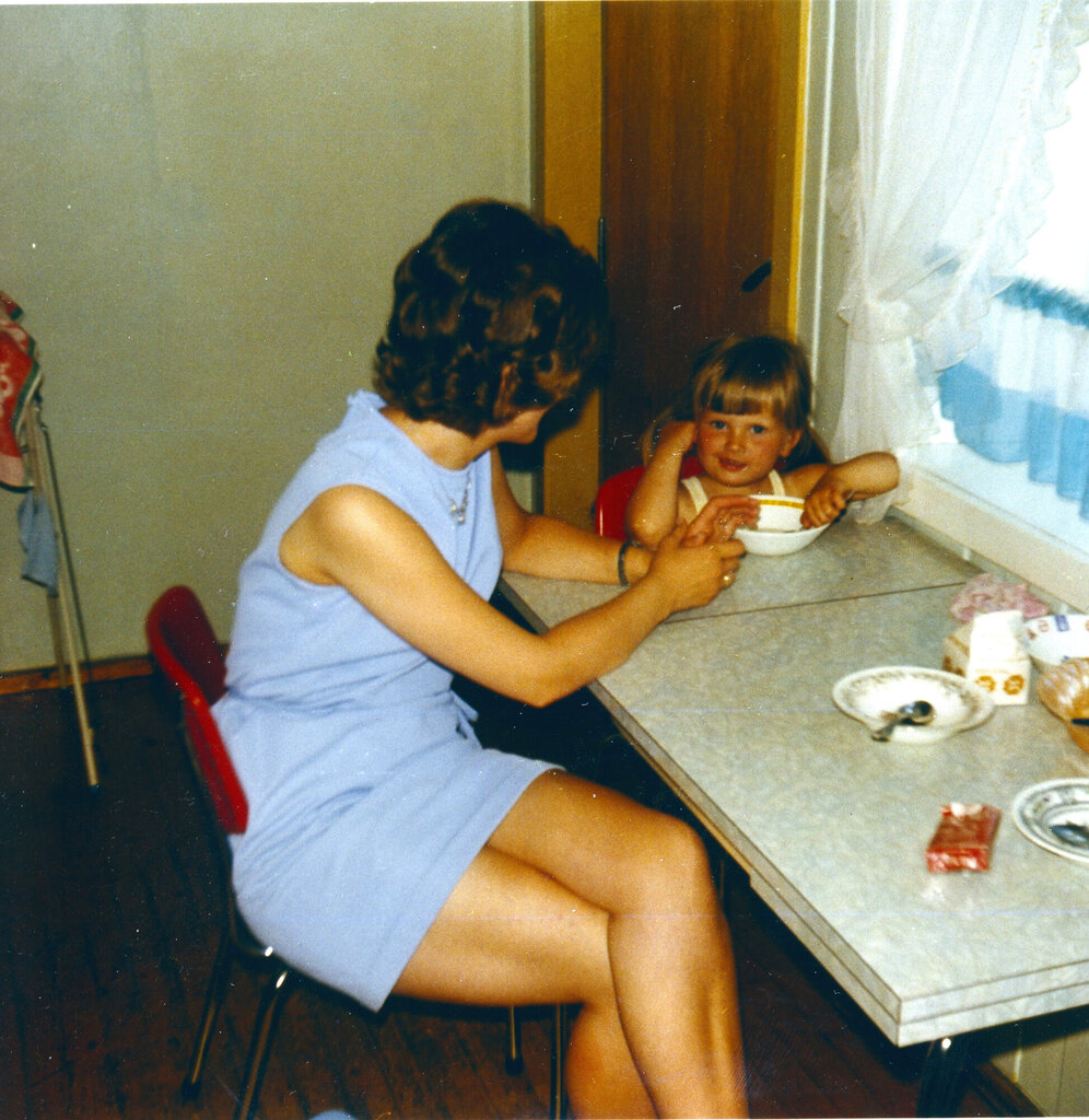 Bildet viser Karin Jonli som barn sammen med moren ved kjøkkenbordet.