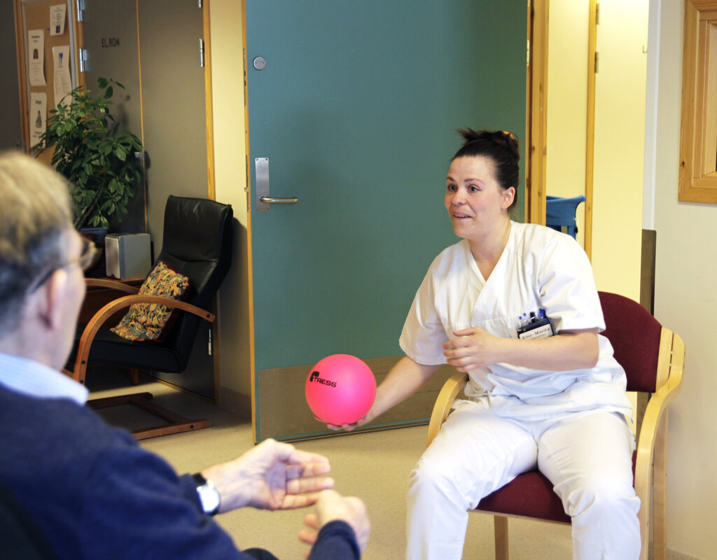 Bildet viser sykepleier Kine-Marita Krüger på Sentrum sykehjem, Bodø som kaster en ball til en eldre pasient som sitter med ryggen til.