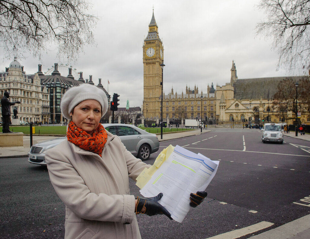 Bildet viser Julie Bailey som holder opp en rapport foran House of Parliament i London.