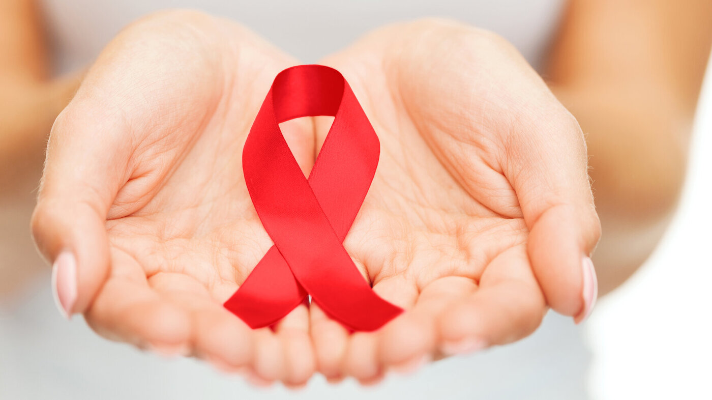 Bildet viser hender som holder en rød sløyfe som symboliserer hiv/aids