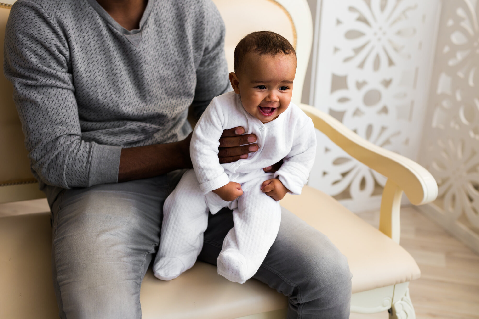 En mann sitter med baby på fanget. Begge er etnisk afrikanske Baby på fanget til sin far