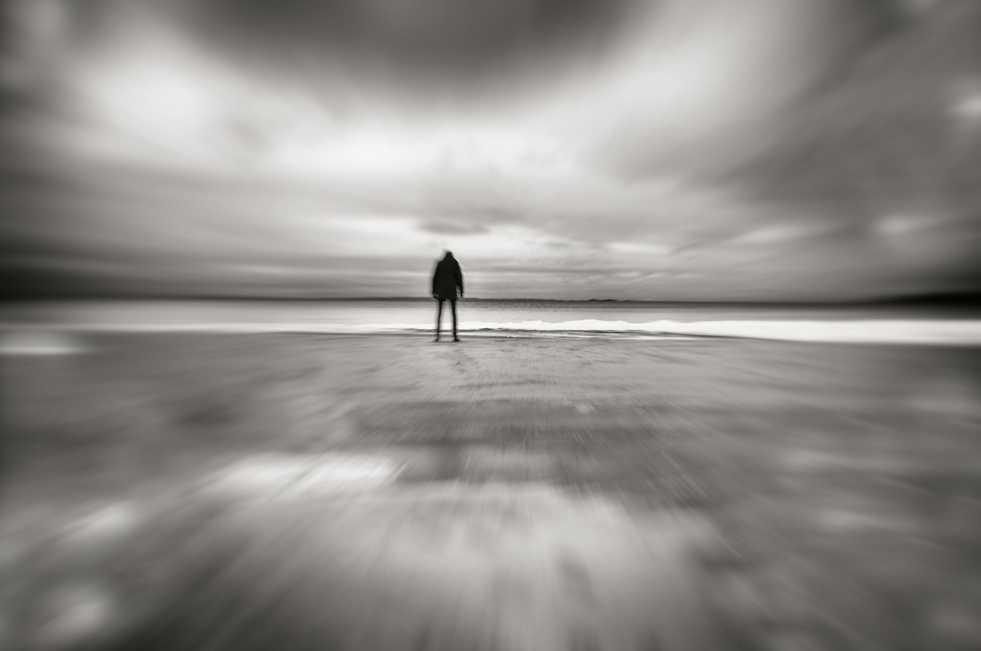 Abstrakt sort-hvitt bilde av en skikkelse som står på en strand og ser ut over havet. Abstrakt sort-hvitt bilde av en skikkelse som står på en strand og ser ut over havet.