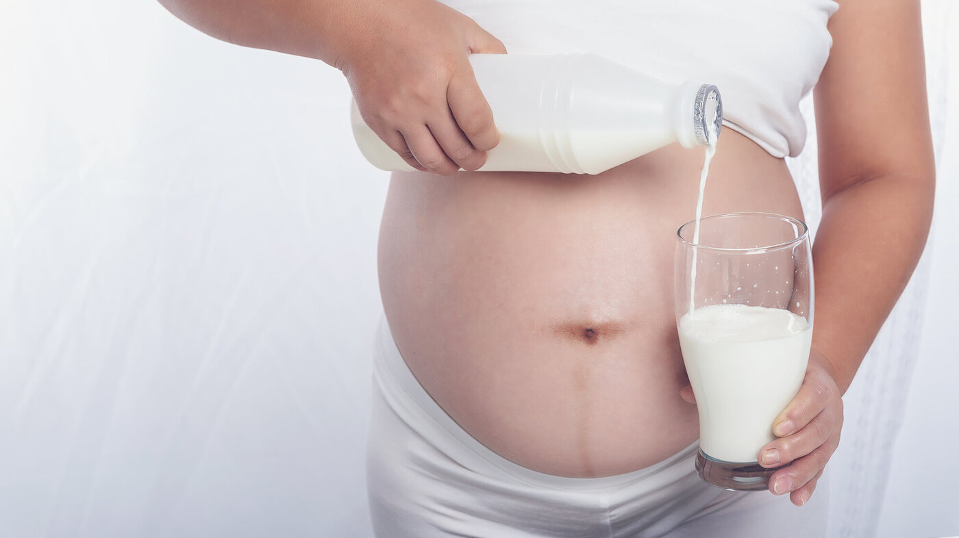Bildet viser en gravid kvinne som skjenker seg et glass melk.
