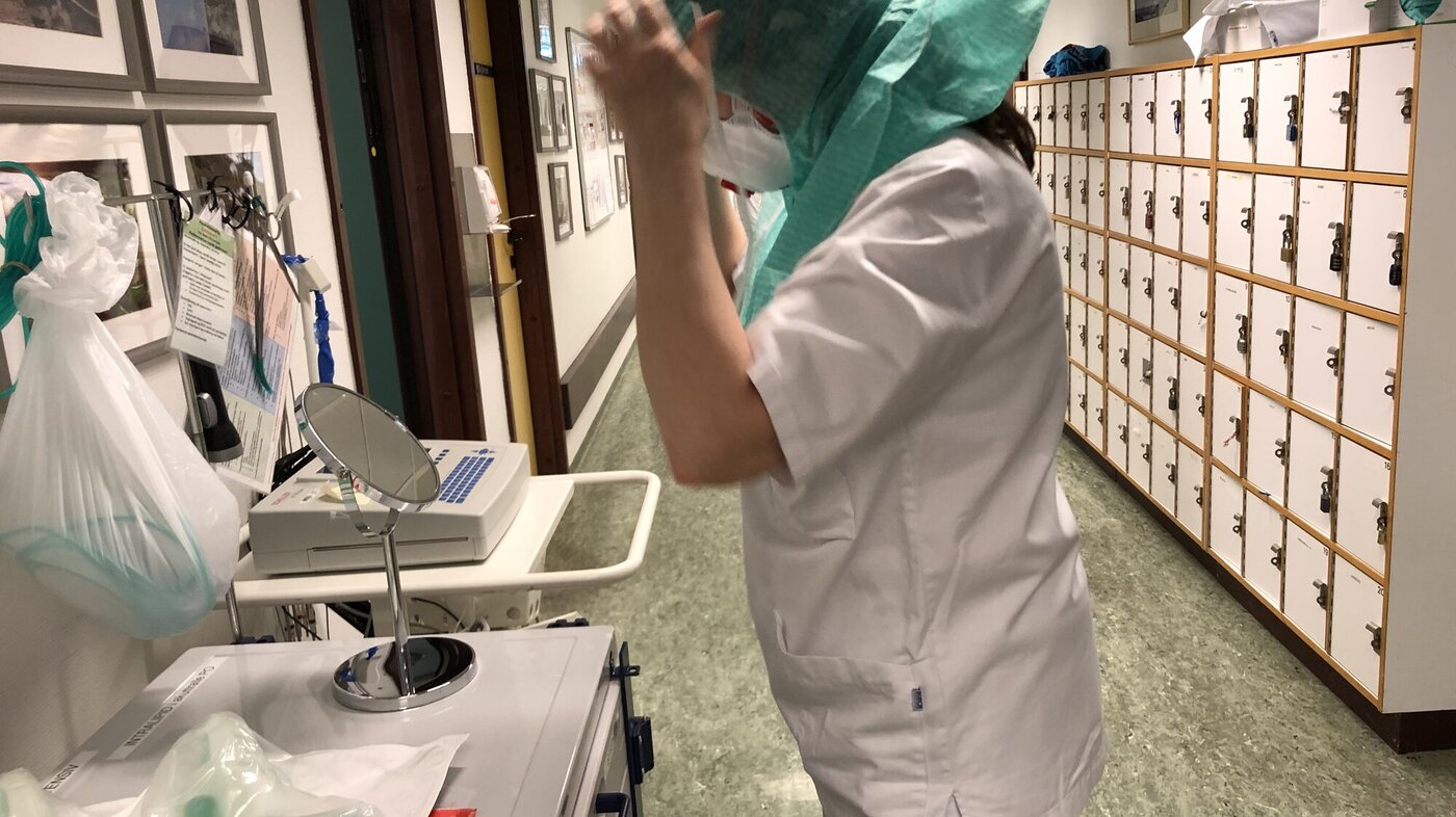 Bildet viser en sykepleier som tar på smittevernutstyr.