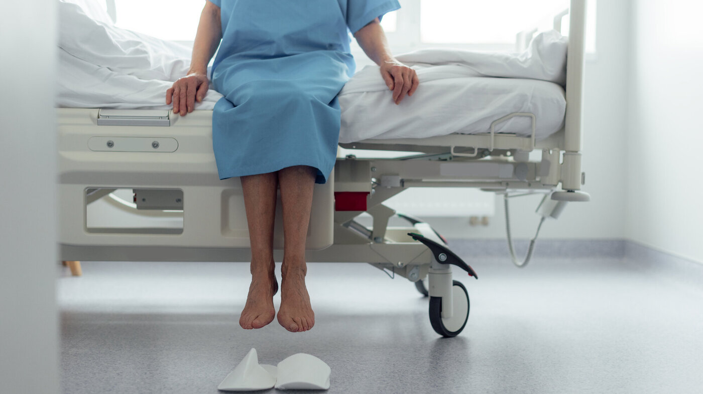 Bildet viser en eldre, oppegående kvinne på sykehus