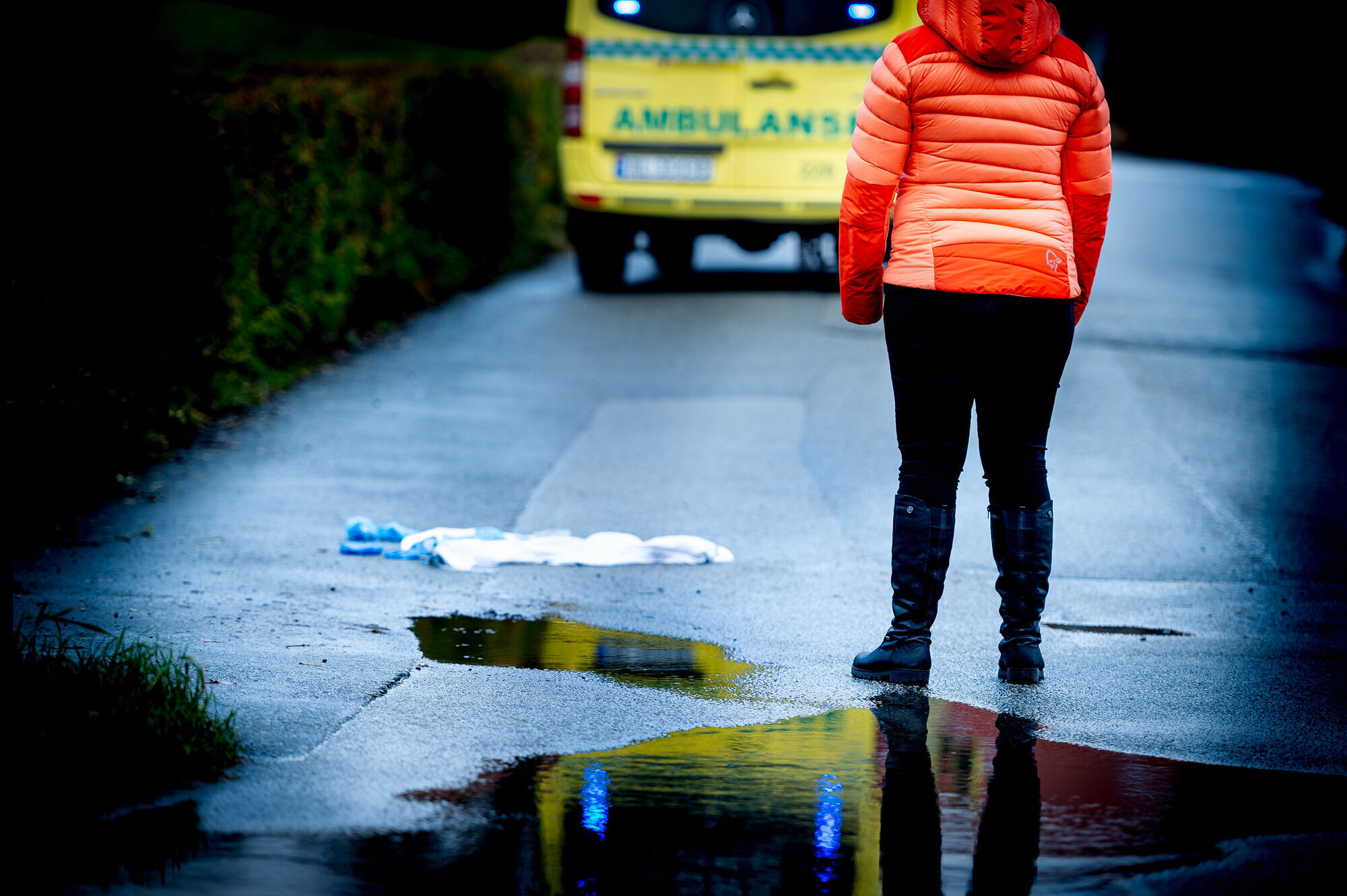 Kvinne står og ser mot ambulanse Kvinne står og ser mot ambulanse