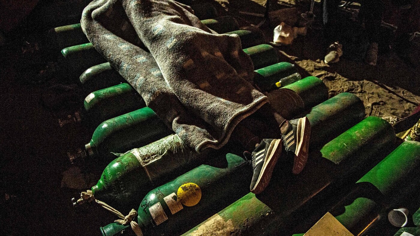 Bildet viser et menneske som sover oppå tomme oksygenflasker.