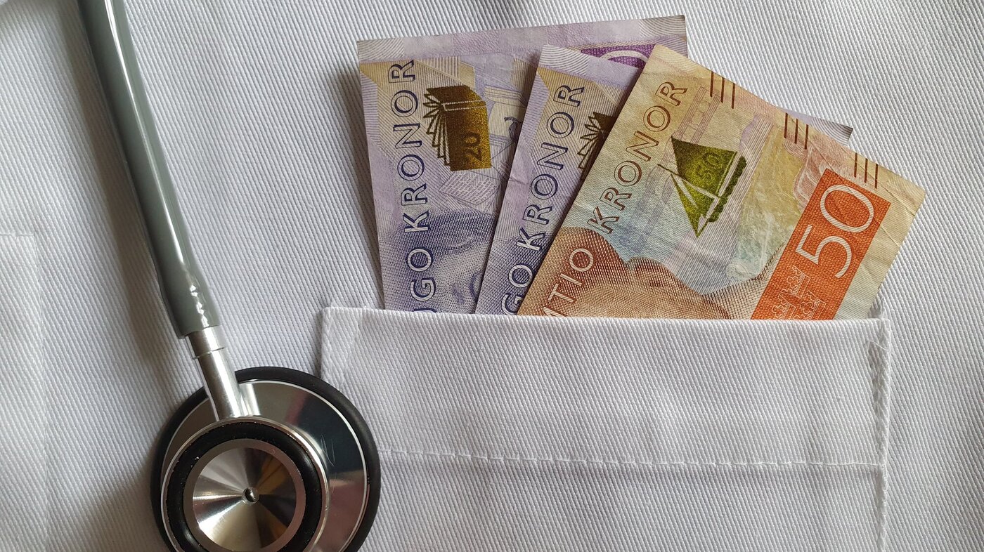 bildet viser en hvit frakkelomme med svenske penger i