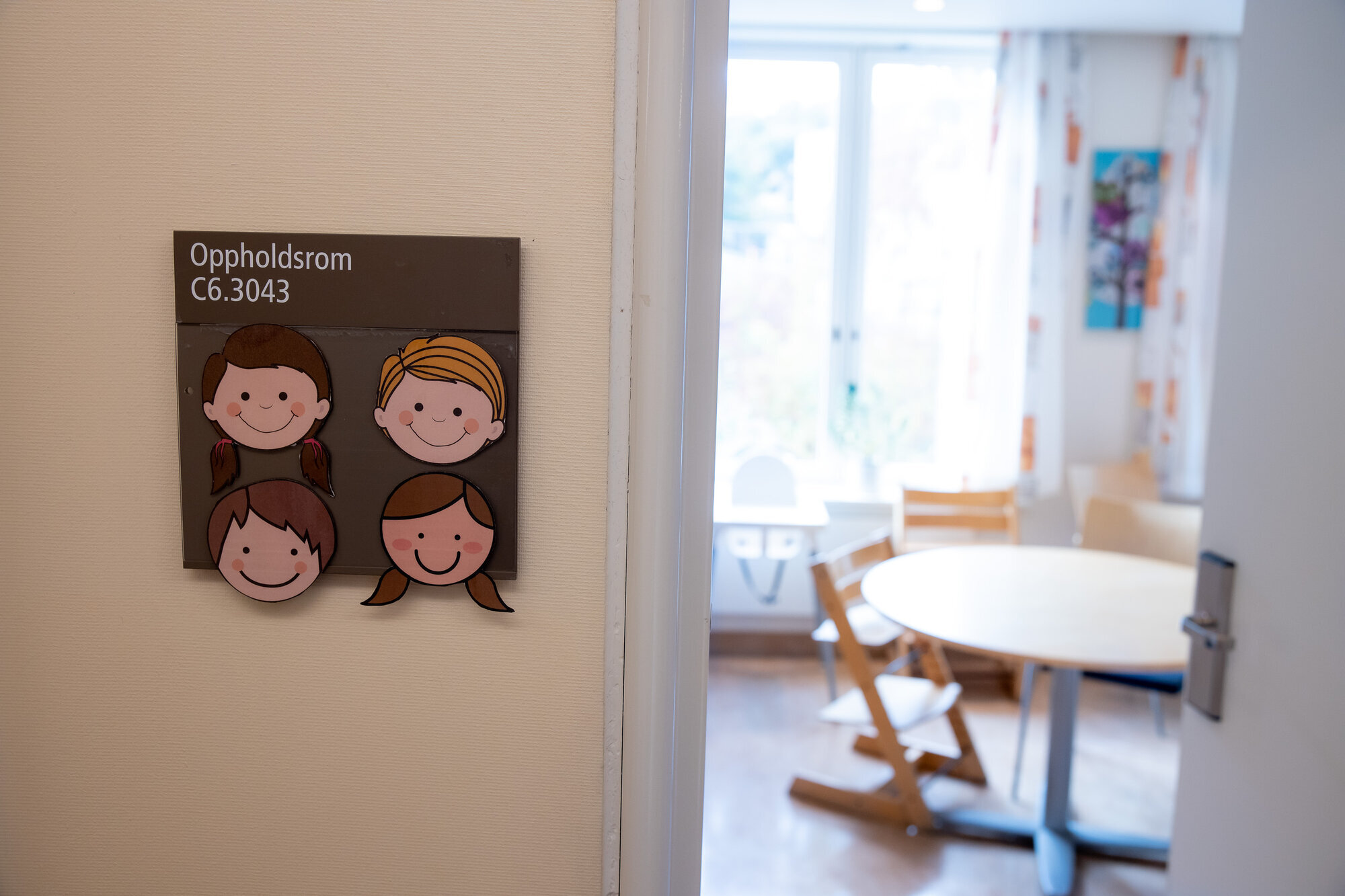 Barneavdeling Bildet viser en åpen dør med et skilt der det står oppholdsrom, og litt av rommet.