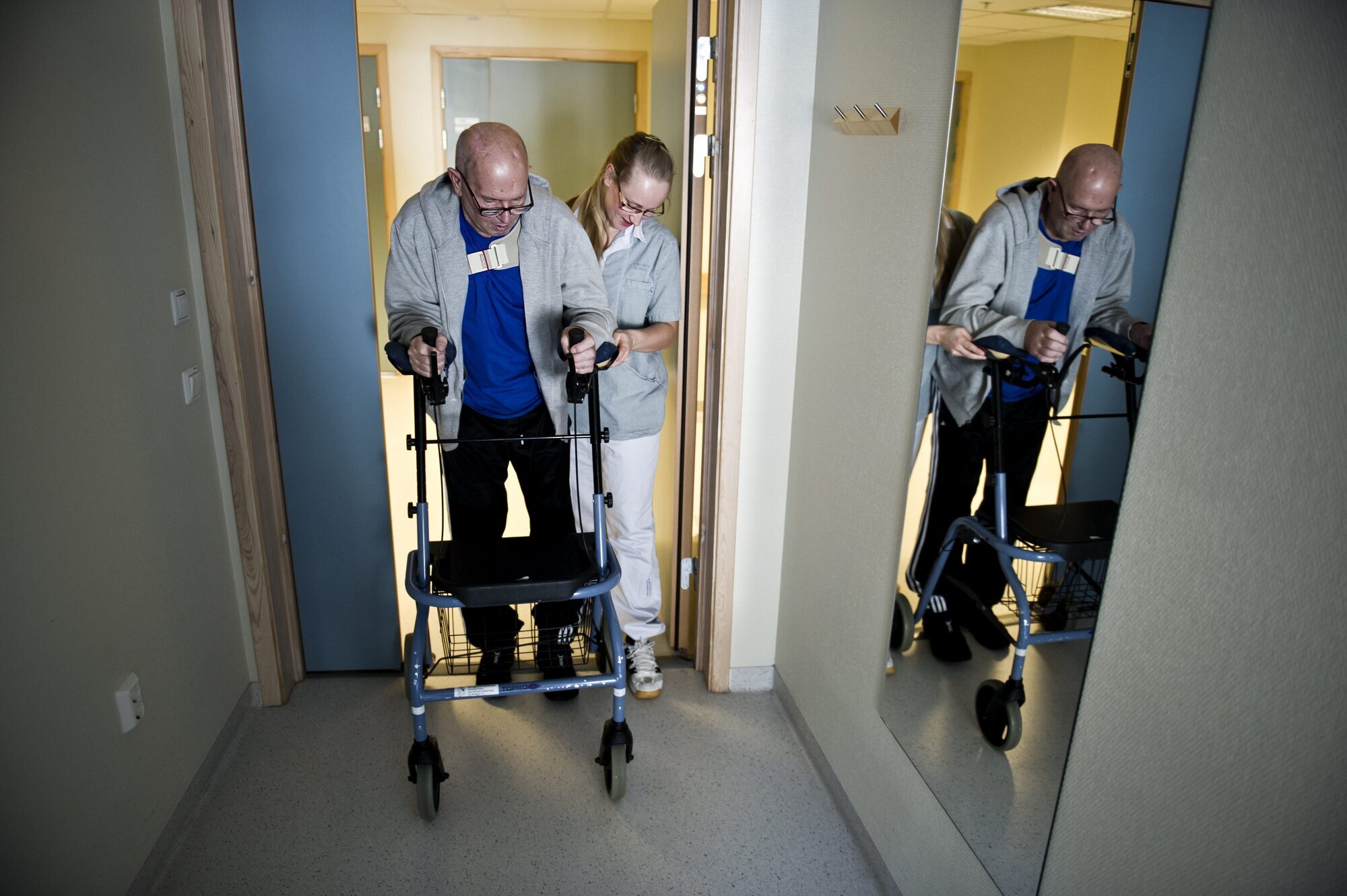 Hofteoperert mann Bildet viser en mann med gåstol, som støttes av en sykepleier