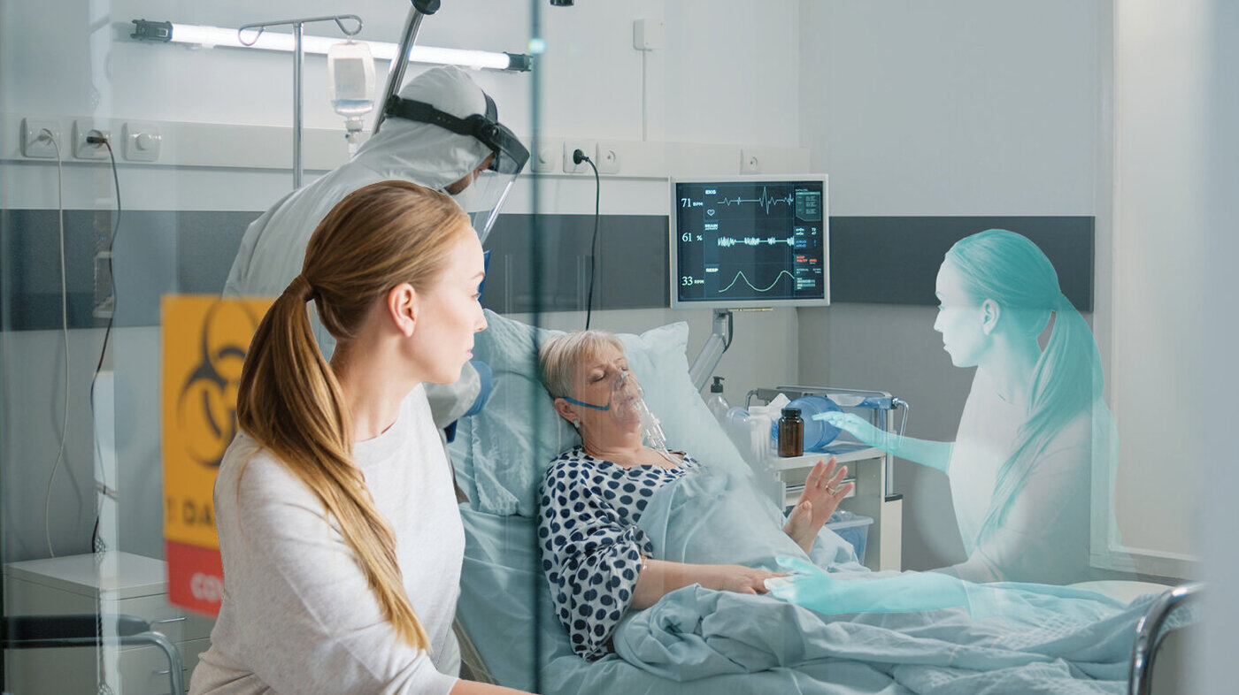 Bildet viser en sy covid-pasient i en sykeseng. En sykepleier i fullt smittevernutstyr står ved siden av. Utenfor vinduet kikker en pårørende kvinne inn, og skyggen av henne kan skimtes ved siden av sengen.
