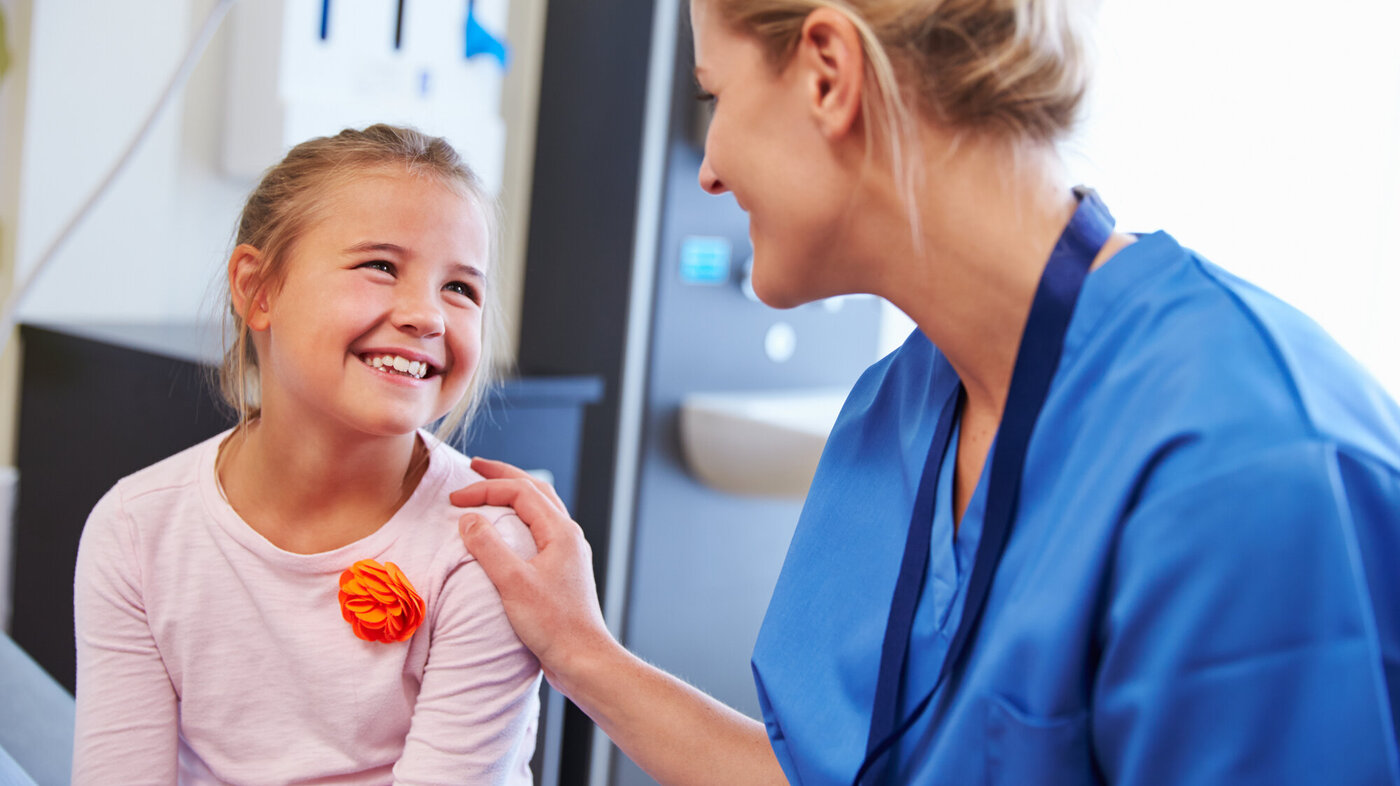 En sykepleier og et smilende barn