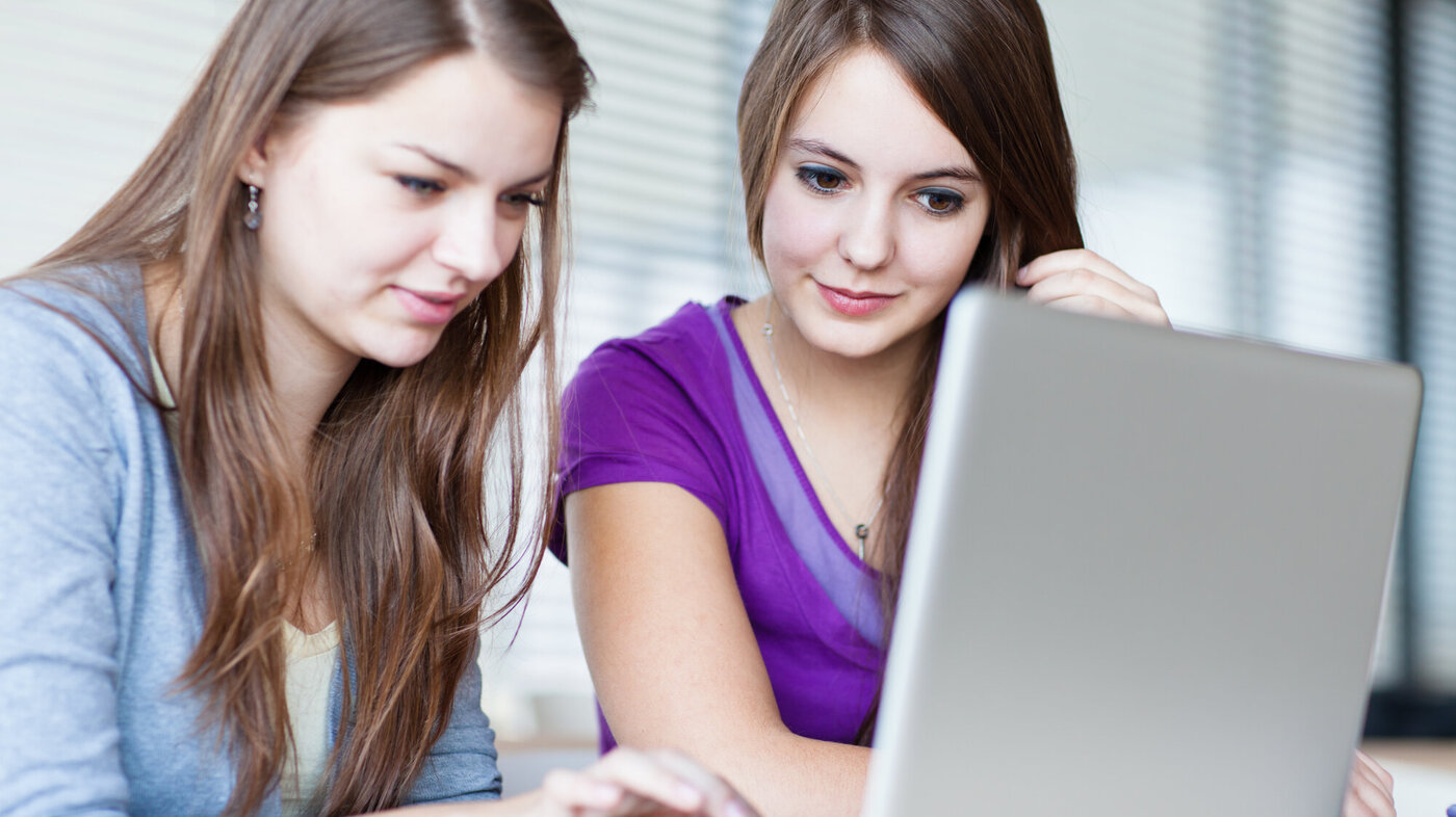 Bildet viser to kvinnelige studenter som ser inn i en pc-skjerm.