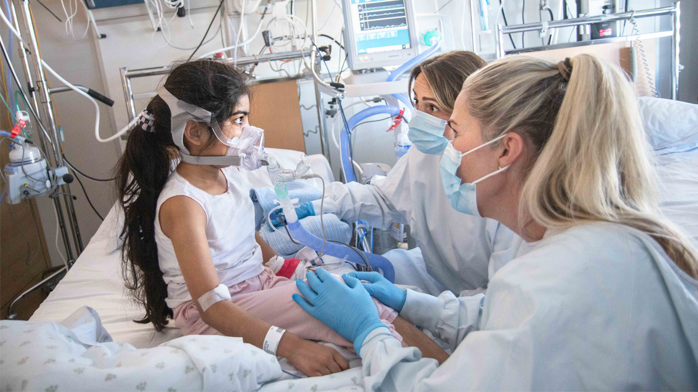 Bildet viser en ung pasient med to sykepleiere.
