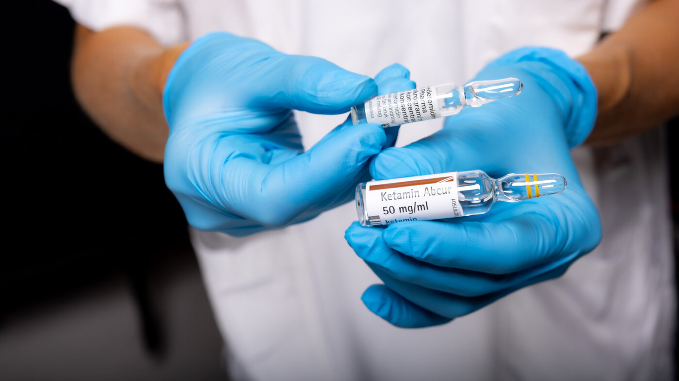 Legemidler for nasal smertelindring Bildet viser to hender med blå hansker som holder to ampuller med legemidlene deksmedetomidin og ketamin